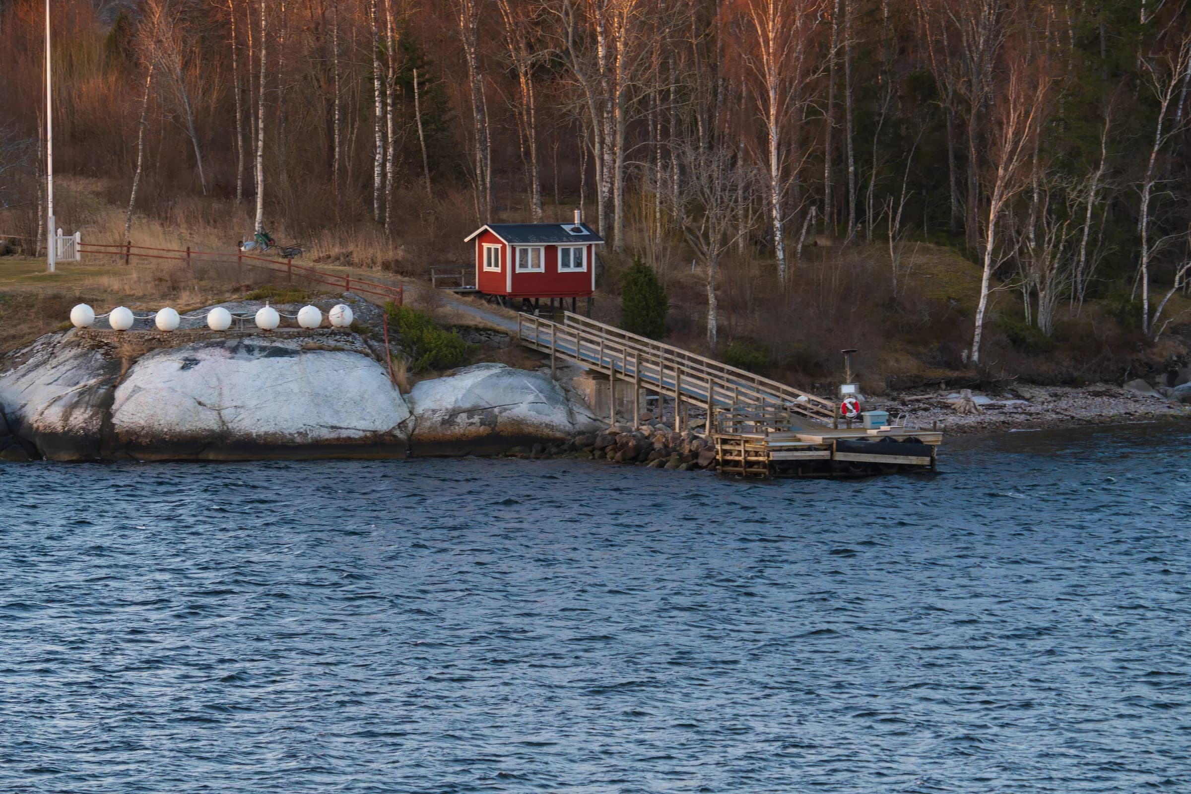 Red cottage with a jetty on the rocks in the archipelago
